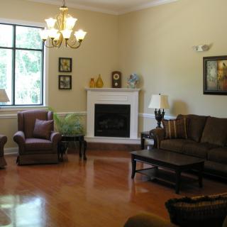 A cozy living room with a fireplace, sofas, and a chandelier.