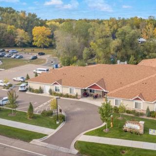 Aerial view of a single-story building with a parking lot and surrounding trees.