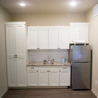A minimalist kitchen setup with white cabinets and stainless steel refrigerator.