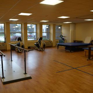 A spacious rehabilitation gym equipped with exercise machines and ample natural light.