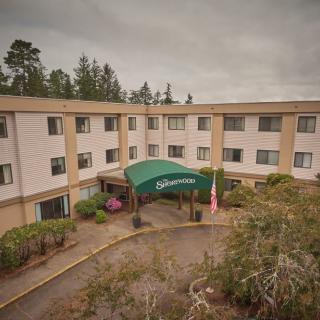 A hotel building with a green canopy entrance surrounded by trees.