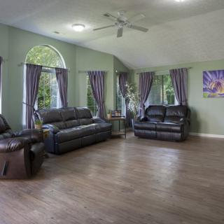 A spacious living room with leather sofas and chairs, featuring elegant curtains and wood flooring.