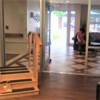 A view of a modern indoor space featuring a staircase leading to a lounge area, with glass doors providing access to an outdoor environment.