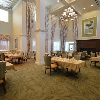 An elegant dining room with tall ceilings, adorned with chandeliers and set for a formal meal.