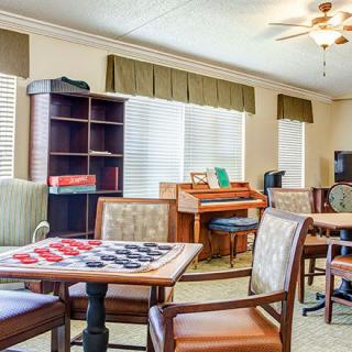 A cozy recreation room featuring game tables, bookshelves, and comfortable seating.