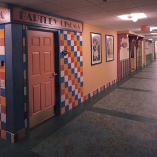 A colorful hallway with multiple doors and tiled wall decorations, resembling a hotel or themed corridor.