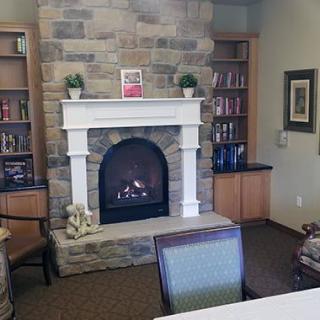A cozy living room with a stone fireplace and bookshelves.