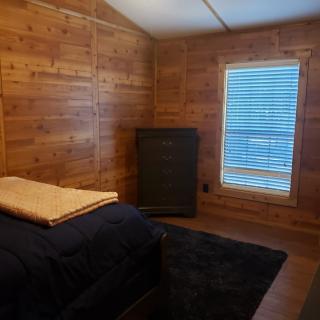 A minimalist bedroom with wood-paneled walls and a single bed.