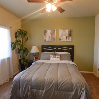 A cozy bedroom featuring a neatly made bed, green walls, and decorative elements.
