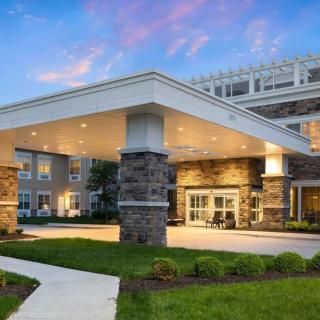 The exterior view of a modern building with a well-lit entrance and landscaped surroundings.