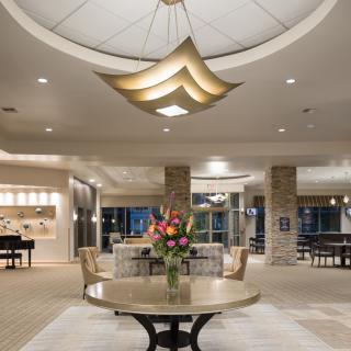 A spacious hotel lobby with elegant lighting, a central table adorned with flowers, and sophisticated interior design.