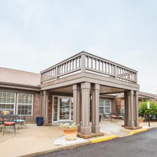 A welcoming entrance to a residential building with an outdoor porch and columns.