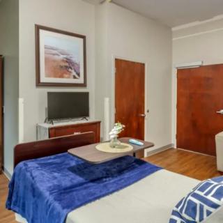 A modern bedroom with a television, wooden furniture, and minimalist decor.