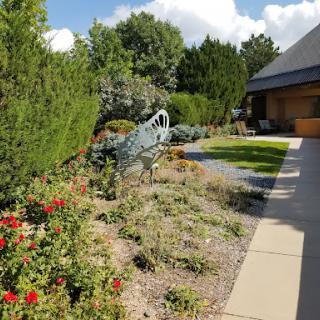 A beautifully landscaped garden featuring a decorative sculpture amidst vibrant flowers and greenery.