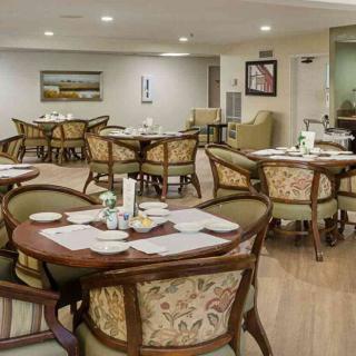 A cozy dining room with elegantly set tables and comfortable chairs, featuring wooden furniture and decor.