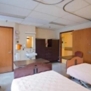 A hospital room with two beds and basic amenities.
