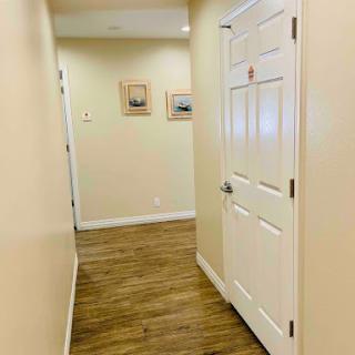 A view of a well-lit hallway featuring wooden flooring and decorative paintings on the walls.