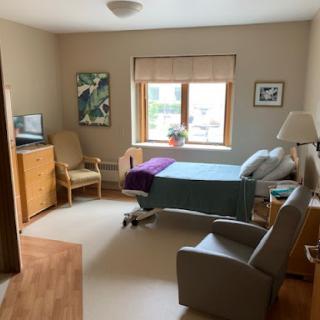 A well-lit hospital room designed for patient comfort, featuring a hospital bed, seating area, and window.