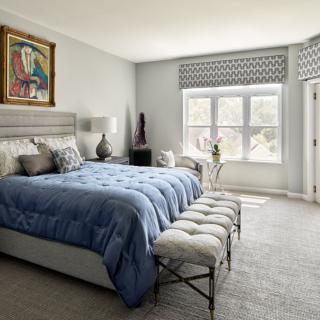 A cozy bedroom featuring a modern design with blue bedding and ample natural light.