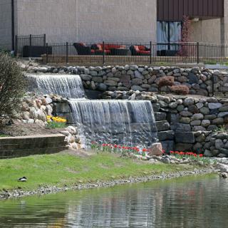 A serene view of a cascading waterfall surrounded by lush greenery and stone features.