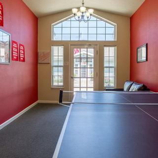 A bright and inviting game room featuring a ping pong table and large windows.