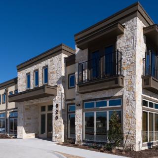 Modern commercial building with stone facade and large windows.