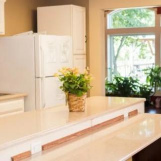 A bright and inviting kitchen with a spacious countertop, potted plants, and large windows letting in natural light.