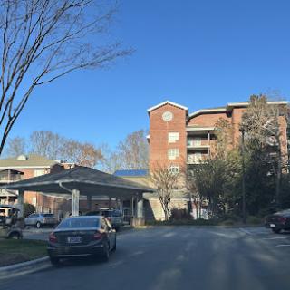 A view of a residential building under a clear blue sky with trees lining the street.