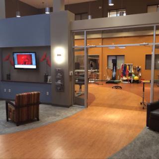 A modern lobby featuring a comfortable seating area, a television display, and an open design leading to another space.