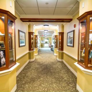A well-lit hallway with display cases showcasing artifacts and framed pictures.