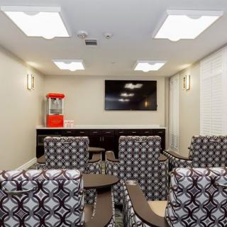 A comfortable home theater room with patterned seating, a mounted television, and a popcorn machine.