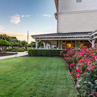 A beautiful backyard with a lush lawn, vibrant flower garden, and a cozy patio area.
