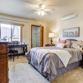Cozy bedroom with a comfortable bed, desk, and natural light through the window.