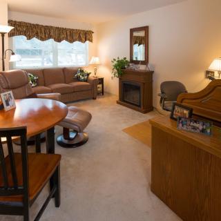 A cozy living room featuring a sectional sofa, coffee table, and dining area with warm lighting.