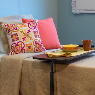 A cozy corner featuring colorful cushions and a tray set on a bed.