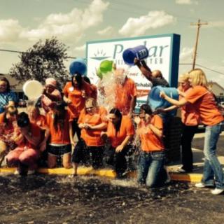 A group of people participating in the Ice Bucket Challenge outdoors, enjoying a charitable event.