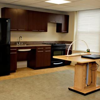 A modern kitchen interior featuring dark wood cabinets, a black refrigerator, and an integrated stove with a countertop island.