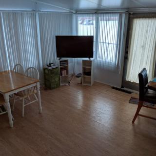 A bright living and dining area with a television, chairs, and wooden flooring.