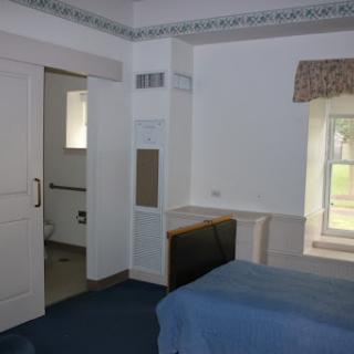 A spacious bedroom featuring blue bedding and a view of the outside through a window.