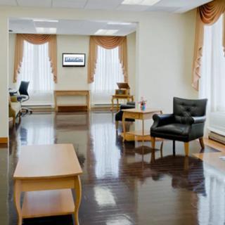 A spacious office interior with polished floors, chairs, and a table.