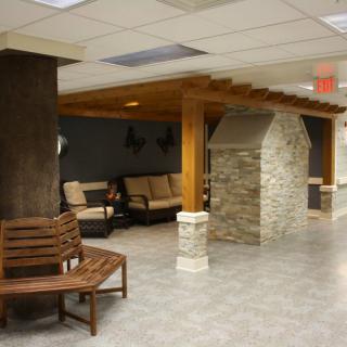 A cozy lobby with wooden and stone features, furnished with benches and seating areas.