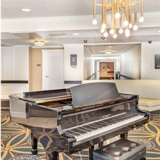 A luxurious hotel lobby featuring a grand piano and modern chandelier.