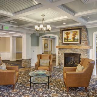 A cozy living room with armchairs around a fireplace, featuring elegant decor and a chandelier.
