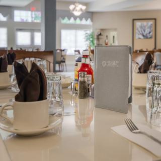 A neatly set dining table in a restaurant with menus, glasses, and condiments.