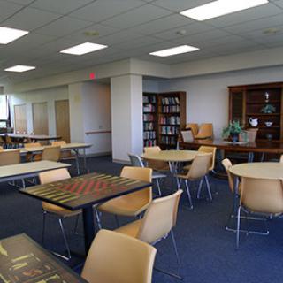 A spacious and well-lit library interior featuring tables and chairs for study.
