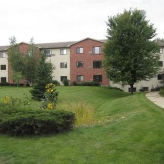 Image of a residential apartment building surrounded by well-maintained greenery and trees.