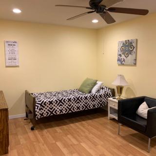 A tidy bedroom with a single bed, a chair, and decorative elements on the walls.