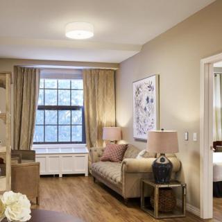A cozy living room with elegant decor, featuring a sofa, lamps, and a large window with curtains.