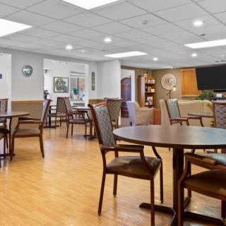 A spacious and well-lit dining area with wooden flooring, tables, and chairs.