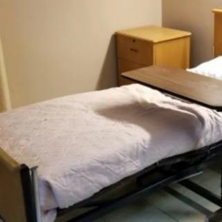 A hospital room with a simple bed and small bedside table.